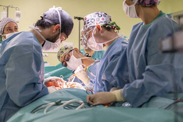 Team of surgeons and nurses performing surgery on patient in operating room - MMPF01038