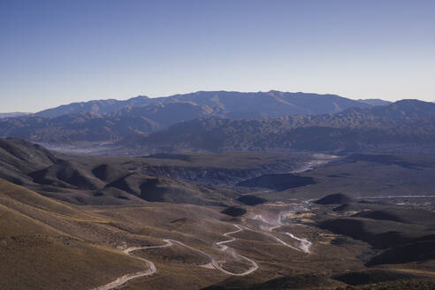 Valley with winding road in front of mountain on sunny day - RSGF01008