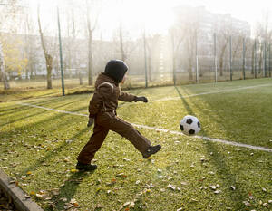Junge kickt Ball auf Fußballplatz - MBLF00174