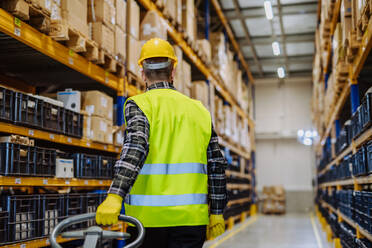 Male warehouse worker dragging the pallet truck. - HPIF31157