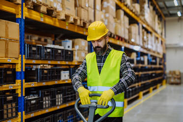 Male warehouse worker pushing the pallet truck. - HPIF31161