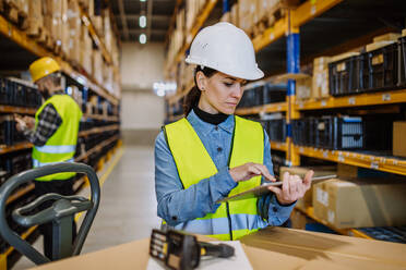 Warehouse workers checking stuff in warehouse with digital system in a tablet, holding a solar panel. - HPIF31190