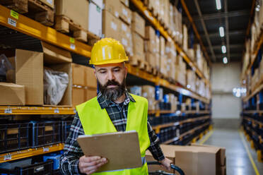 Male warehouse worker dragging the pallet truck. - HPIF31201