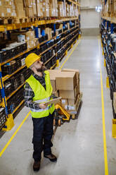 Male warehouse worker dragging the pallet truck. - HPIF31203