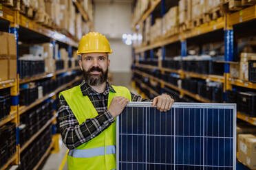 Portrait of warehouse worker with a solar panel. - HPIF31210