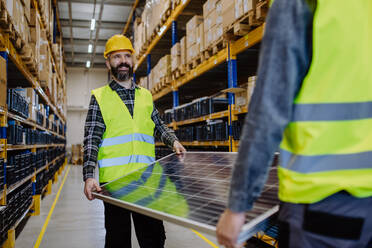 Warehouse workers in a reflective vests carring the solar panel. - HPIF31211