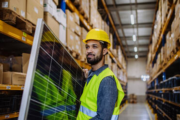 Portrait of warehouse worker carring a solar panel. - HPIF31218