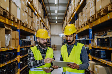 Warehouse workers checking stuff in warehouse with digital system in a tablet. - HPIF31220