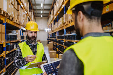 Warehouse workers checking stuff in warehouse with digital system in a tablet. - HPIF31221