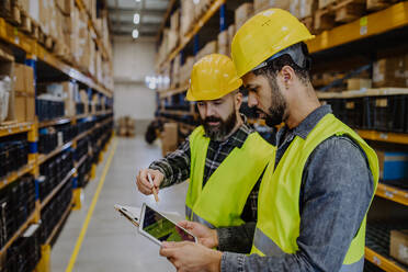 Warehouse workers checking stuff in warehouse with digital system in a tablet. - HPIF31224