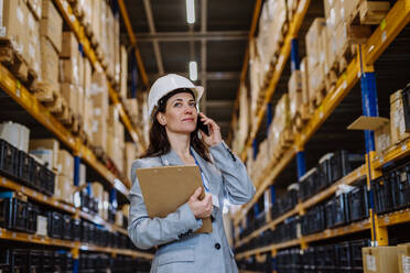 Manager woman in suit calling in warehouse. - HPIF31248