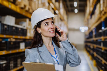 Manager woman in suit calling in warehouse. - HPIF31249