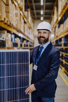 Porträt eines Managers mit einem Solarpanel in einem Lagerhaus. - HPIF31251