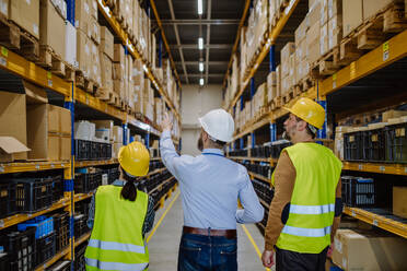 Manager explaining work to his employers in a warehouse. - HPIF31256