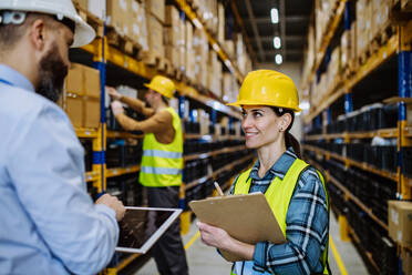 Manager explaining work to his employers in a warehouse. - HPIF31257