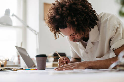 Young multiracial man drawing something in a designers studio. - HPIF31283