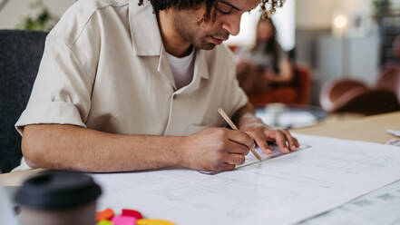 Young multiracial man drawing something in a designers studio. - HPIF31285