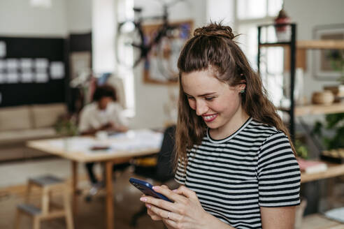 Young woman having break at work, scrolling her smartphone. - HPIF31307