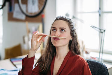 Portrait of a funny woman with pencil in mouth, having fun at work. - HPIF31337