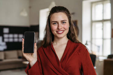 Portrait of young smiling woman with smartphone in office. - HPIF31344