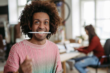 Portrait of a funny man with pen in mouth, having fun at work. - HPIF31349