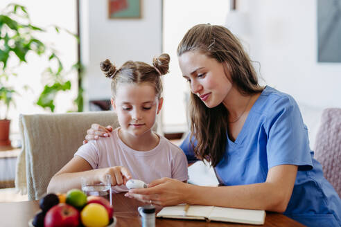 Nurse checking girl's blood glucose level using a fingerstick glucose meter. Endocrinologist waiting for results from blood test. - HPIF31352