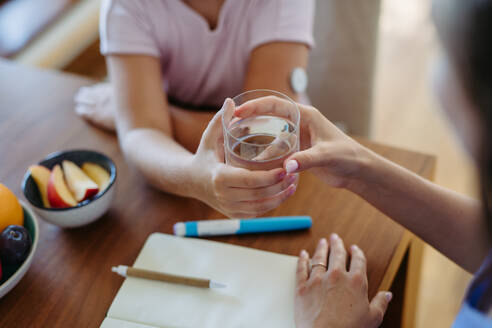 Girl drinking water to better manage her diabetes. Continuous glucose monitor sensor on girl's arm. - HPIF31357