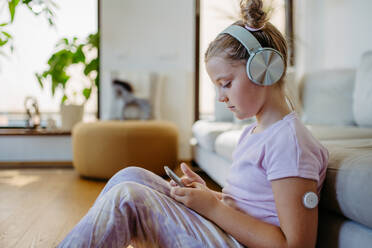 Diabetic girl watching social media content on smart phone.The CGM device makes the life of the schoolgirl. easier, helping manage his illness and focus on other activities. - HPIF31361