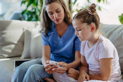 Nurse checking girl's blood glucose level using a fingerstick glucose meter. Endocrinologist waiting for results from blood test. - HPIF31365