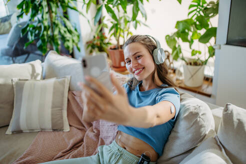 Beautiful diabetic girl taking a selfie, having an insulin pump and a continuous glucose monitor on her arm. Young woman is not ashamed of having diabetes, sharing her life with a chronic illness on social media. - HPIF31370