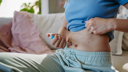 Close-up shot of a diabetic woman injecting insulin into her abdomen, belly. - HPIF31373