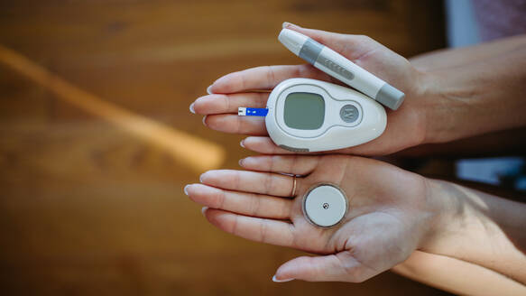 Nahaufnahme von Händen, die Diabetes-Zubehör und -Geräte halten. Kontinuierlicher Glukose-Monitor, Insulin-Pen, Blutzuckermessgerät. Banner mit Kopierbereich. - HPIF31376