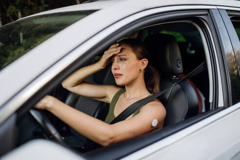 Woman with diabetes feeling dizzy during car drive. Diabetic woman with CGM needs to raise her blood sugar level to continue driving. - HPIF31385