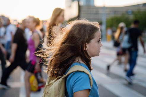 Seitenansicht eines Mädchens mit Rucksack, das auf dem Weg zur Schule den Fußgängerüberweg überquert. Konzept des Schulanfangs. - HPIF31394