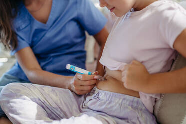 Krankenschwester spritzt Insulin in den Bauch eines diabetischen Mädchens. Nahaufnahme eines jungen Mädchens mit Typ-1-Diabetes, das Insulin mit einer Spritze einnimmt. - HPIF31407