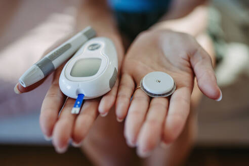 Nahaufnahme von Händen, die Diabetes-Zubehör und -Geräte halten. Kontinuierlicher Glukose-Monitor, Insulin-Pen, Blutzuckermessgerät. Banner mit Kopierbereich. - HPIF31411