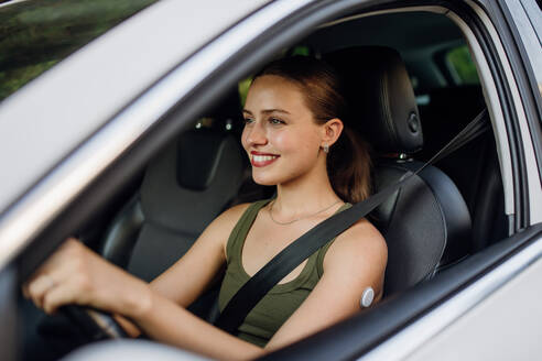 Woman with continuous glucose monitor driving car. Diabetic woman with CGM needs to raise her blood sugar level to continue driving car. - HPIF31424