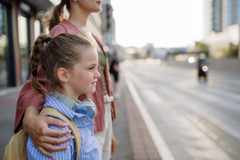 Mutter und Schulmädchen mit Rucksack halten sich an den Händen, während sie eine belebte Straße überqueren. Konzept der Rückkehr zur Schule. - HPIF31428