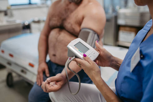 Ein Arzt misst den Blutdruck, untersucht den Bluthochdruck und verwendet ein Blutdruckmessgerät. Übergewicht beeinträchtigt die Gesundheit von Männern mittleren Alters. Konzept der Gesundheitsrisiken von Übergewicht und Fettleibigkeit. - HPIF31458