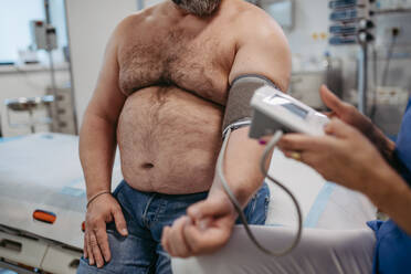 Ein Arzt misst den Blutdruck, untersucht den Bluthochdruck und verwendet ein Blutdruckmessgerät. Übergewicht beeinträchtigt die Gesundheit von Männern mittleren Alters. Konzept der Gesundheitsrisiken von Übergewicht und Fettleibigkeit. - HPIF31459