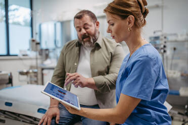 Female doctor consulting with the overweight patient, discussing test result in doctor office. Obesity affecting middle-aged men's health. Concept of health risks of overwight and obesity. - HPIF31466