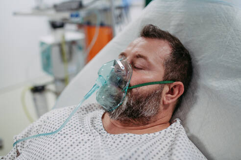 Bewusstloser Patient mit Sauerstoffmaske auf dem Krankenhausbett, Mann auf der Intensivstation im Krankenhaus. - HPIF31483