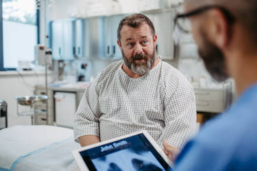 Ein Arzt zeigt einem übergewichtigen Patienten eine Röntgenaufnahme der Brust und bespricht das Ergebnis in der Notaufnahme. Atemwegserkrankungen bei Männern mittleren Alters. Konzept der Gesundheitsrisiken von Übergewicht und Adipositas. - HPIF31487