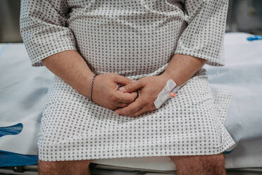 Rückansicht eines übergewichtigen Patienten im Krankenhauskittel, der auf die medizinische Untersuchung und die Testergebnisse im Krankenhaus wartet und sich ängstlich, besorgt und verängstigt fühlt. - HPIF31488
