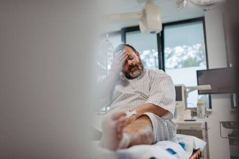 Übergewichtiger Patient im Krankenhauskittel, der auf die ärztliche Untersuchung, die Testergebnisse im Krankenhaus wartet und sich ängstlich fühlt. Der Patient fühlt sich schwindlig, hat Schwindel und starke Schmerzen. - HPIF31491