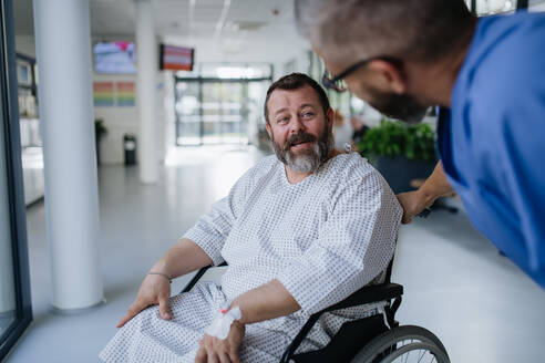 Unterstützende Krankenschwester beruhigt besorgte Patientin im Rollstuhl. Krankheiten bei Männern mittleren Alters. Mitfühlender Arzt im Gespräch mit gestresster Patientin. Konzept der Gesundheitsrisiken von Übergewicht und Adipositas. - HPIF31507