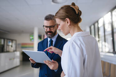 Pharmaceutical sales representative talking with the female doctor in medical building. Hospital director consulting with healthcare staff. - HPIF31524