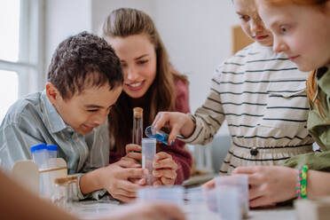 Young teacher doing chemistry experiment with her pupils during science education. - HPIF31545