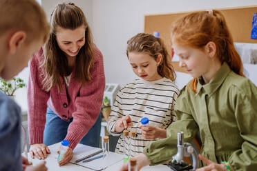 Junge Lehrerin bei einem Chemieexperiment mit ihren Schülern im naturwissenschaftlichen Unterricht. - HPIF31547