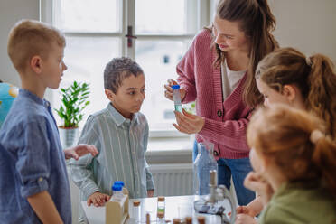 Young teacher doing chemistry experiment with her pupils during science education. - HPIF31550